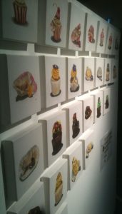 A wall with lots of paintings of cupcakes
